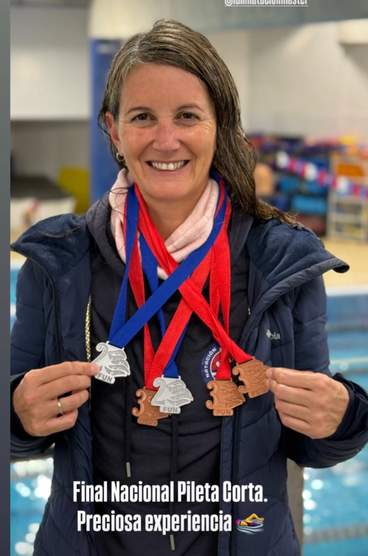 Dani sonriendo en la pileta con cinco medallas de la Final Nacional de Pileta Corta